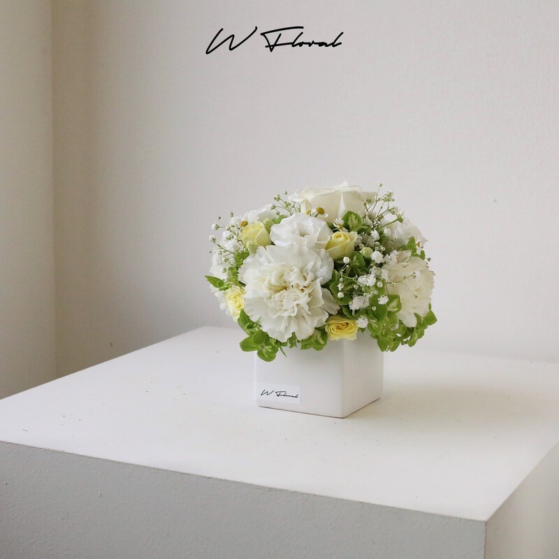 Compact white floral table centrepiece in square vase