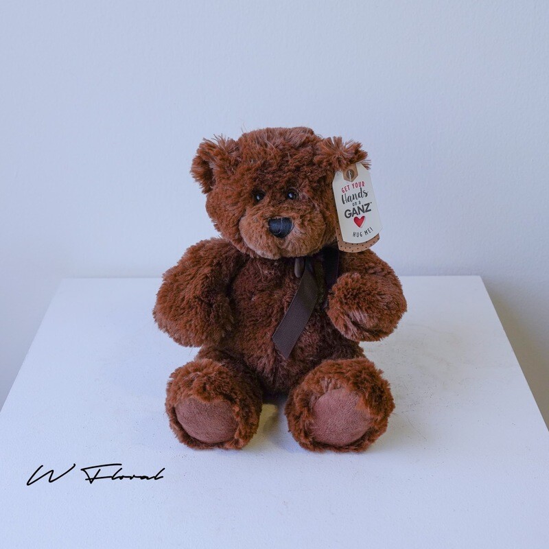 Soft cuddly teddy bear gift presented alongside fresh flowers