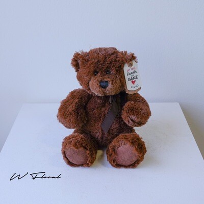 Soft cuddly teddy bear gift presented alongside fresh flowers
