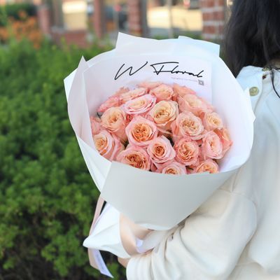 Structured salmon pink rose bouquet in contemporary round wrapping