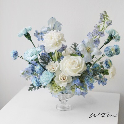 Airy seasonal flower arrangement in transparent glass bowl