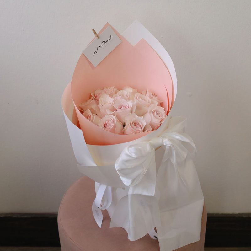 Soft pink rose bouquet in a rounded Canelé style with elegant white ribbon
