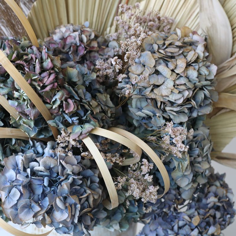 Sculptural dried flower arrangement in earthy neutral and blue tones