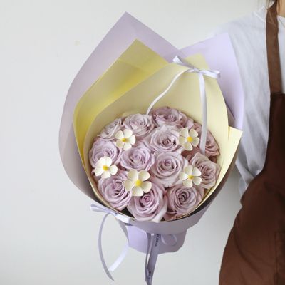 Lavender roses with yellow buttercup accents in a hand-tied bouquet