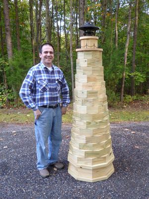 Carpenter standing next to a lighthouse he built