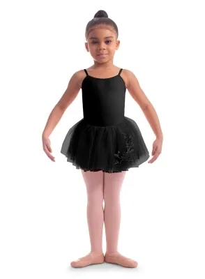 Junge Ballerina in schwarzem Tutu mit floraler Stickerei, rosa Strumpfhose und Schläppchen, posiert auf weißem Grund.