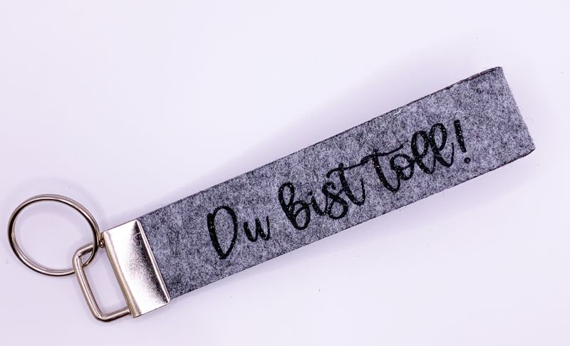 Schlüsselanhänger Filzoptik, Schlaufe, grau meliert, schwarz glitzer "Du bist toll!"