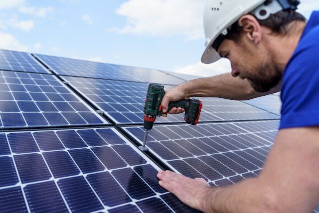 Worker fixing a solar panel to a roof