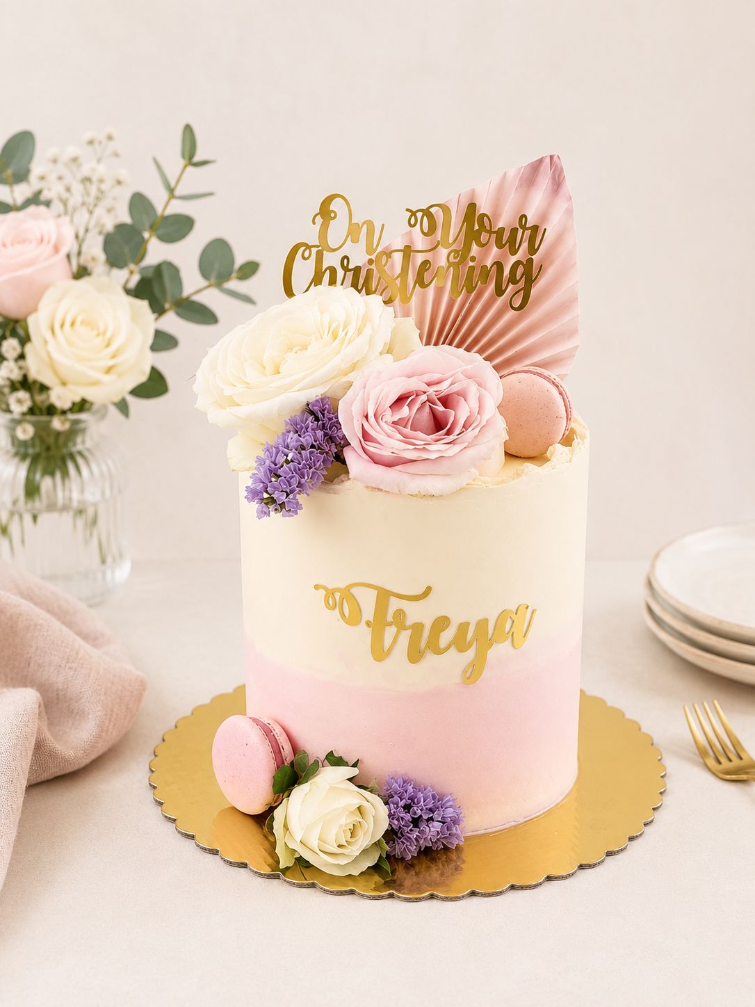 Pink floral christening cake decorated with fresh flowers and almond macarons