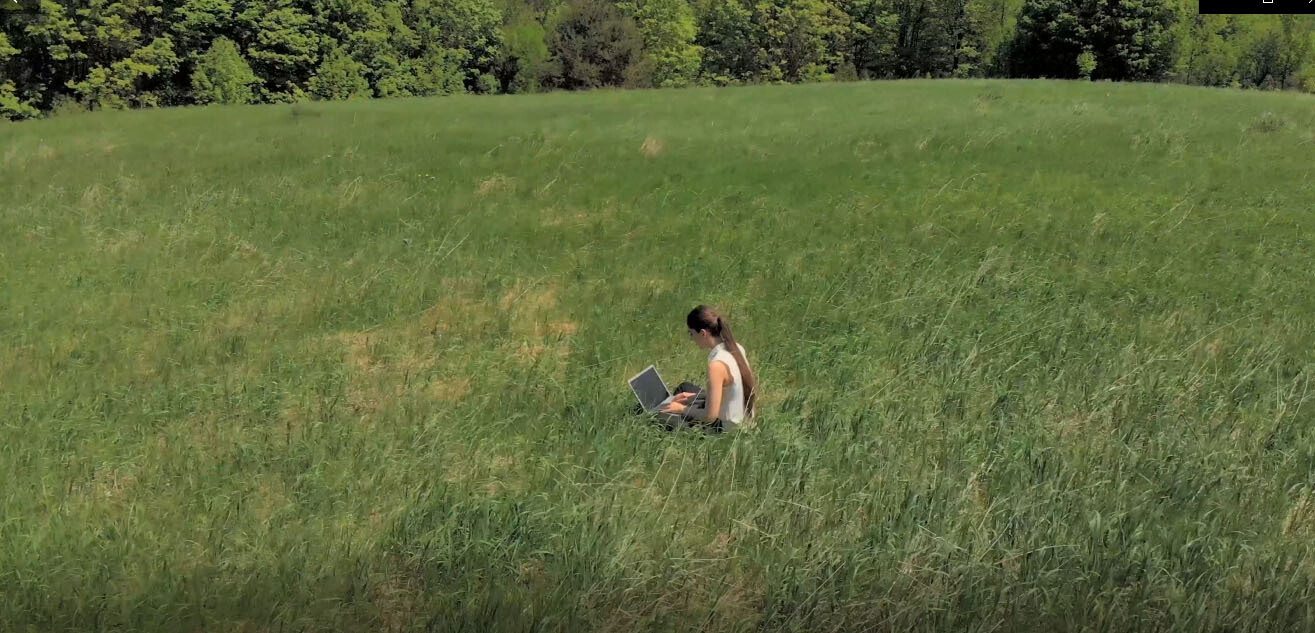 Young woman working on laptop in field. (A) Young woman working on laptop in field. (A)