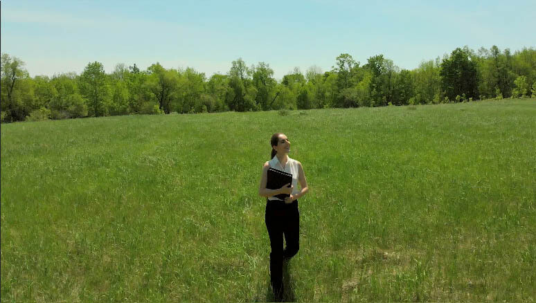 Young woman strides towards you holding an office book in a sunny field. (7) Young woman strides towards you holding an office book in a sunny field. (7)