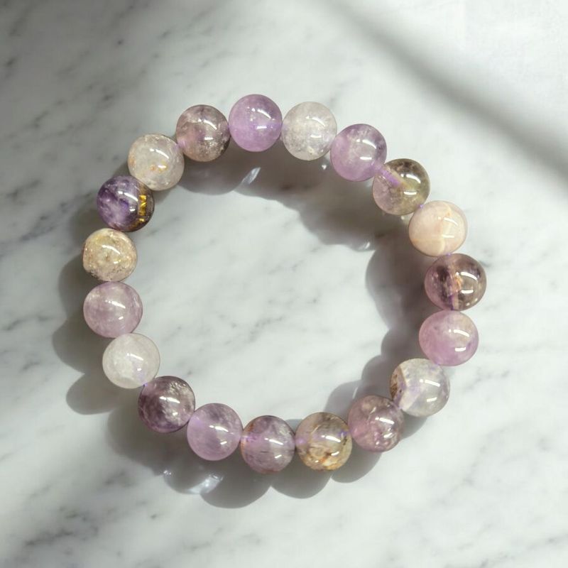 Auralite 23 10mm stretch bracelet with purple and earthy tones on marble background.