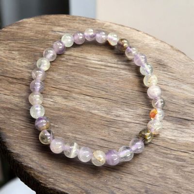 Auralite 23 6mm bead stretch bracelet with soft lavender and neutral tones displayed on wood surface.