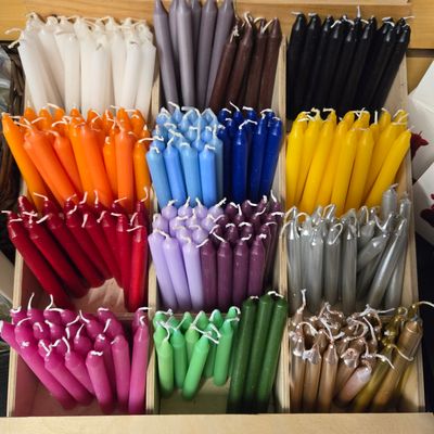 Assorted 4-inch chime candles in multiple metaphysical colors arranged in a wooden display