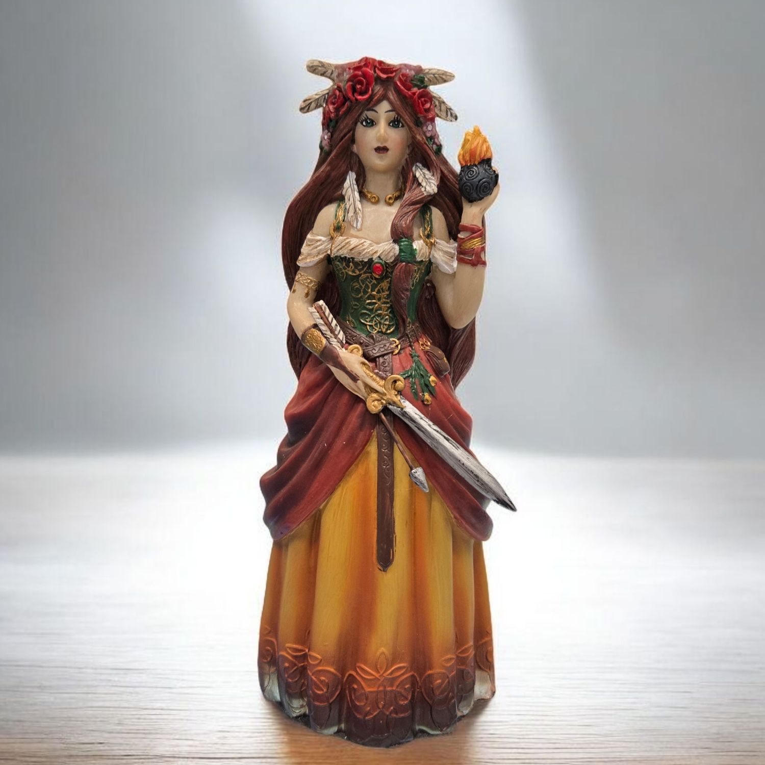 Colorful Brigid statue holding flame and sword, Celtic goddess of fire, healing, and creativity.