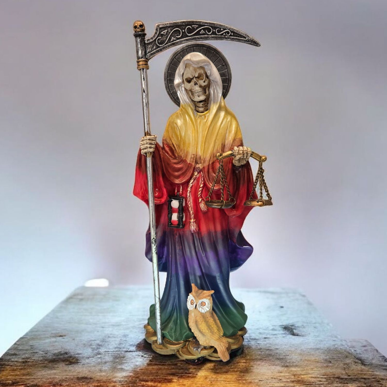 Hand-painted Santa Muerte rainbow statue with multi-colored robe, scythe, and globe, symbolizing full-spectrum blessings.