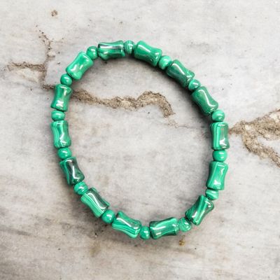 Malachite unique beads stretch bracelet with polished green banded stones displayed on a light marble surface
