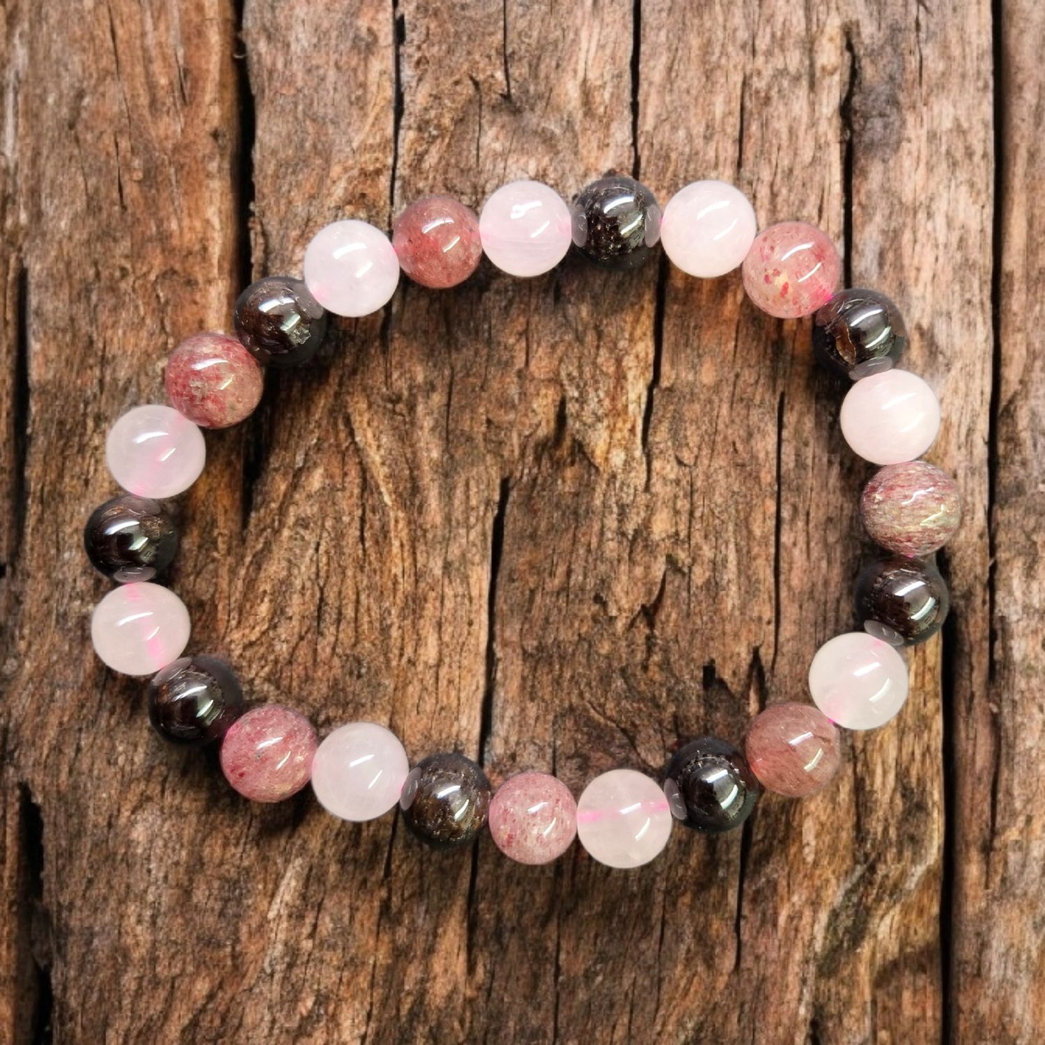 GARNET/STRAWQUARTZ/ROSEQUARTZ 8MM BRACELET Garnet Strawberry Quartz Rose Quartz 8mm stretch bracelet with mixed pink and dark gemstone beads on rustic wood
