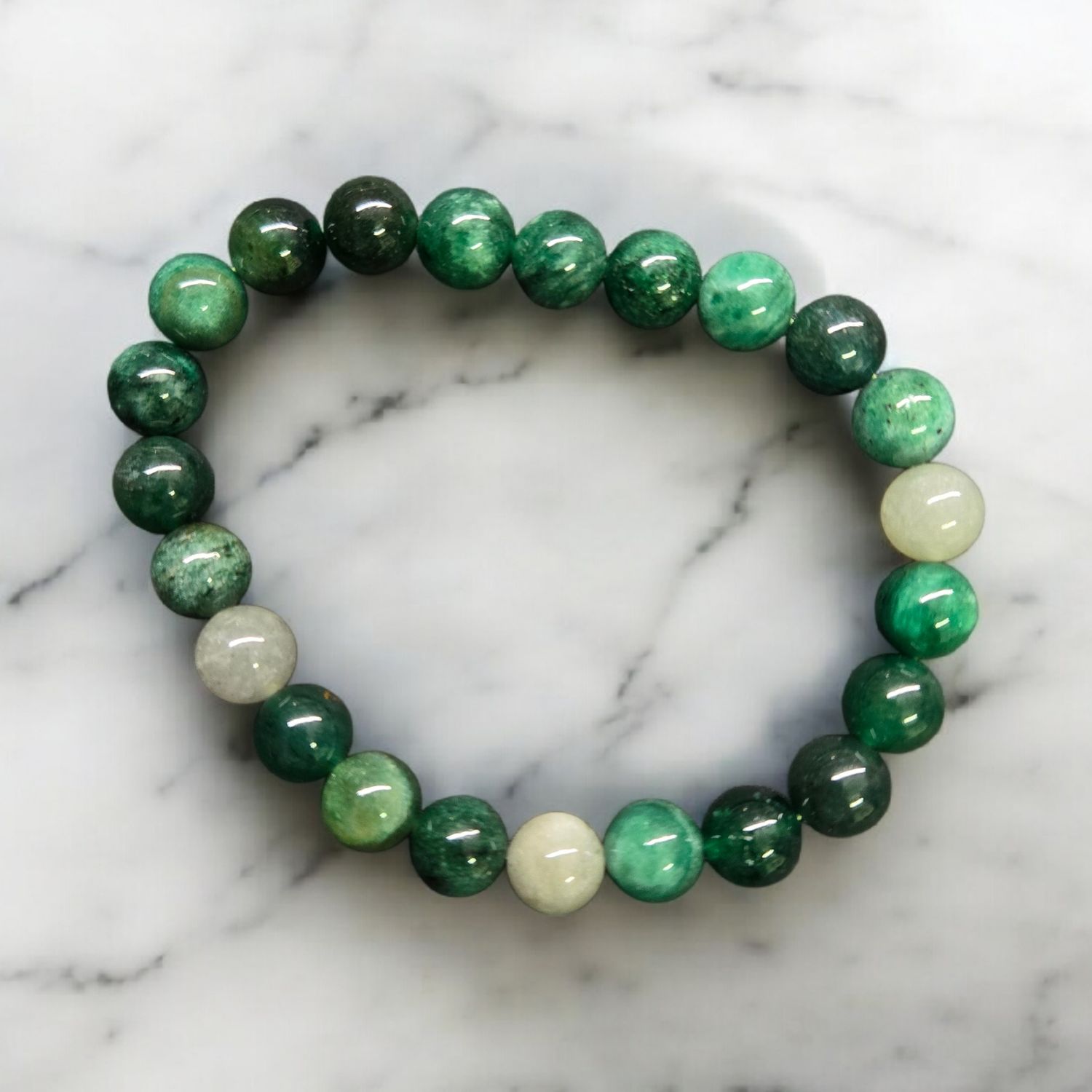 Green lepidolite 8mm stretch bracelet with mixed green polished beads on white marble background