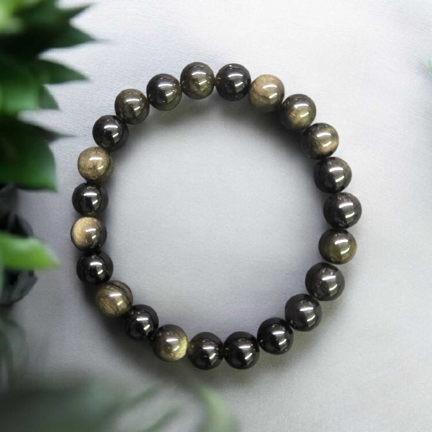 Goldsheen obsidian 8mm stretch bracelet on stone surface with soft lighting