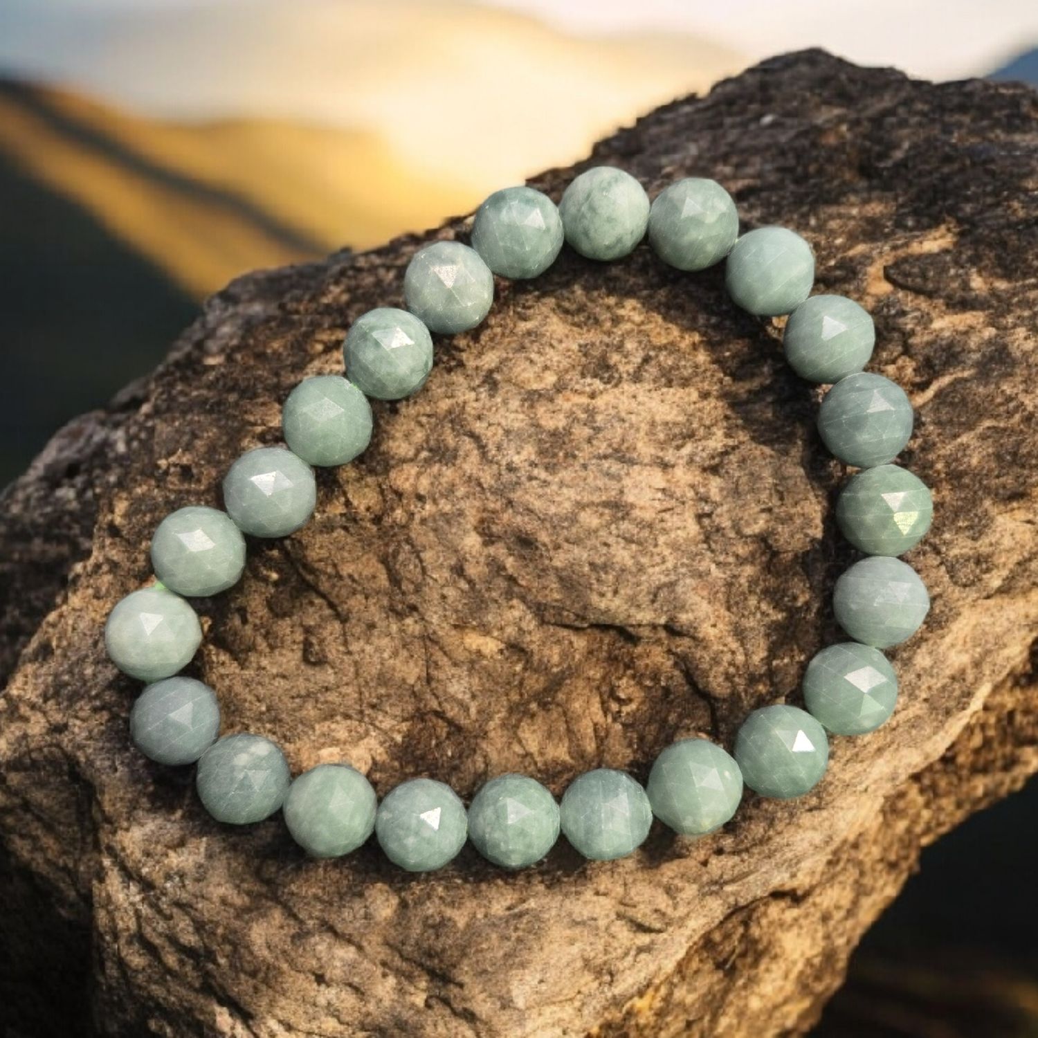 Close-up of faceted jade jadeite 8mm beaded stretch bracelet on stone at sunset