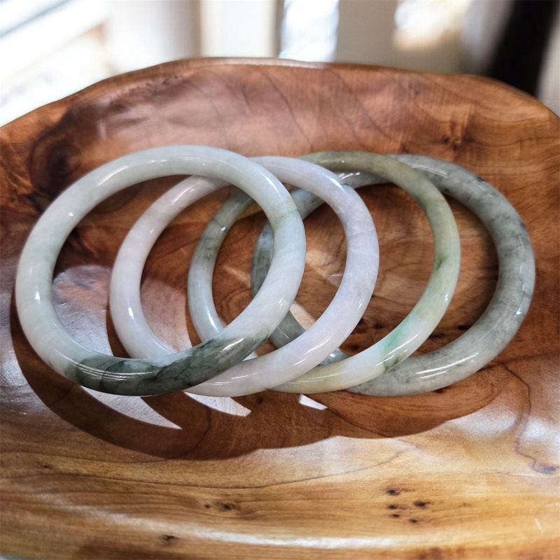 6mm Burmese jade bangle bracelet with natural green and white tones displayed on a wooden tray