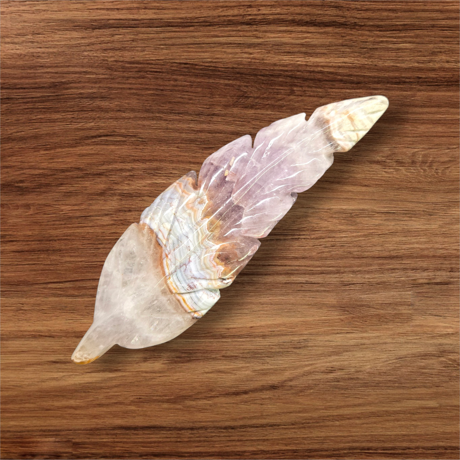 Amethyst Lace Agate feather crystal carving with lavender and cream banding, approx 4.5 inches long on wooden surface