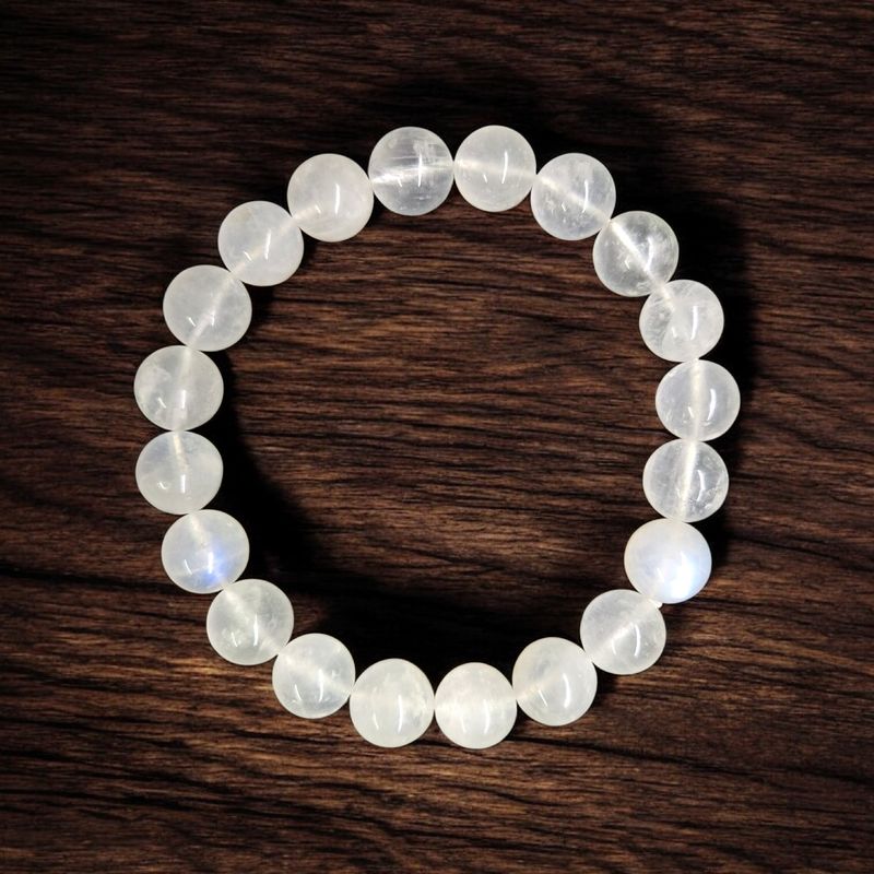 Moonstone 10mm bead bracelet with polished round stones on a stretch cord, displayed on a wooden background.