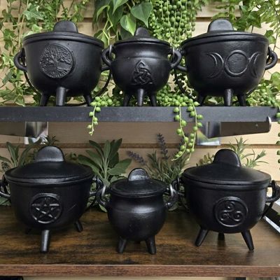 Cast iron ritual cauldrons on altar shelf with pentagram, triple moon, and tree of life designs at Arkadys Metaphysical Gifts