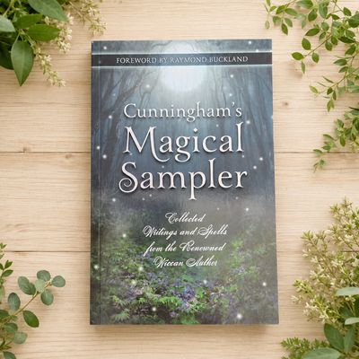 Cunningham’s Magical Sampler by Scott Cunningham on a light wooden table with greenery.