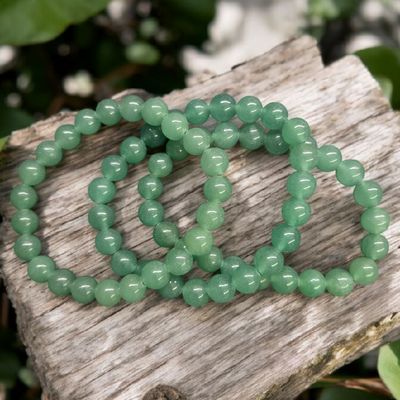 Green aventurine 8mm stretch bracelets arranged on rustic wood with fern leaves
