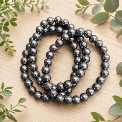 Multiple Polished Hematite 8mm stretch bracelets with reflective dark metallic gemstone beads.