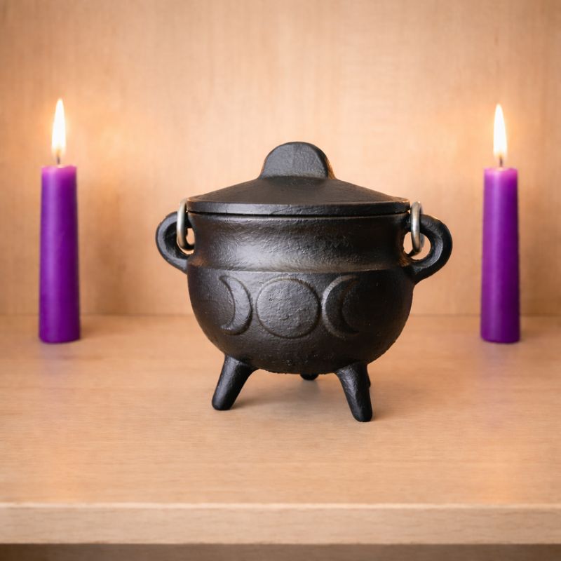 Small cast iron triple moon cauldron with lid on wooden altar with candles from Arkadys Metaphysical Gifts Amarillo TX