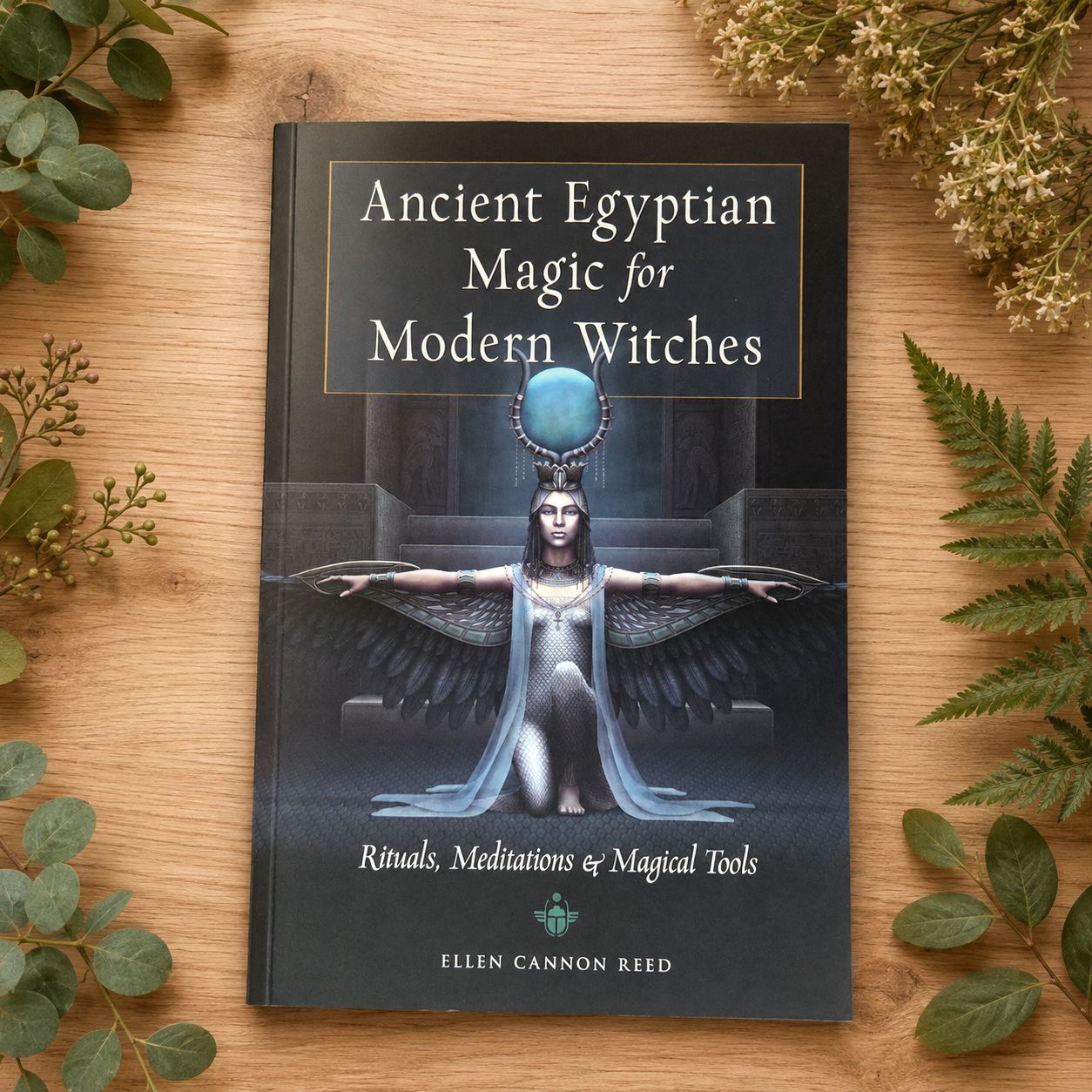 Ancient Egyptian Magic for Modern Witches by Ellen Cannon Reed displayed on light wood with greenery.