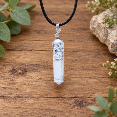 Howlite wire wrap point necklace with silver-tone wire and black cord displayed on natural wood with greenery.
