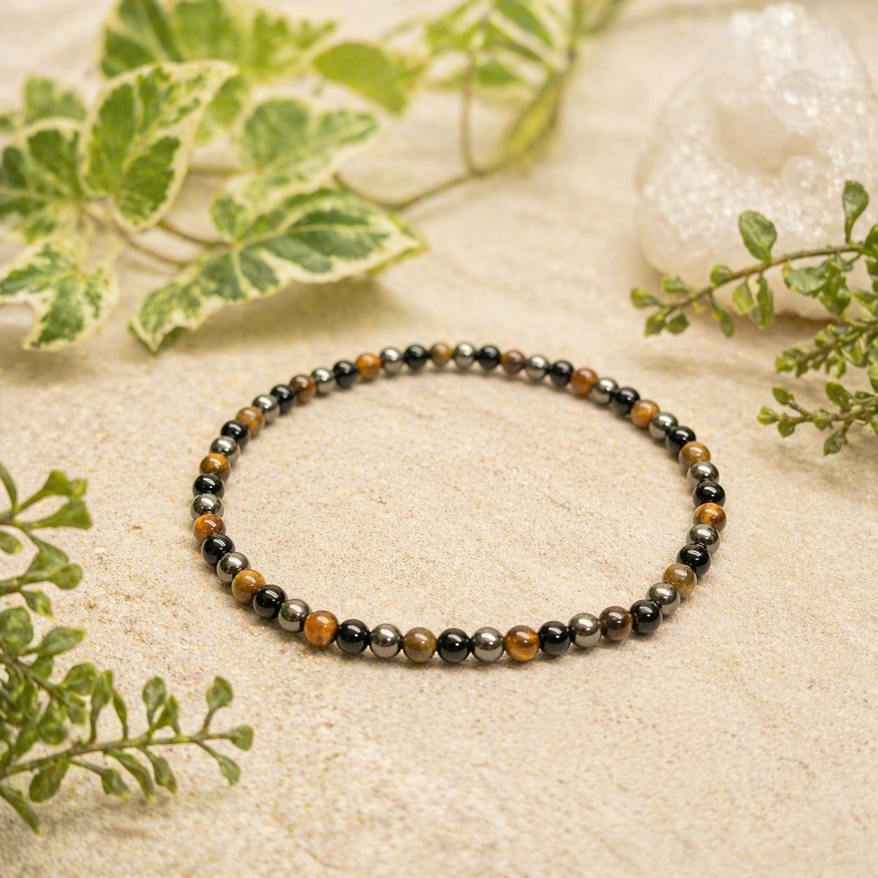 Tigereye Onyx Hematite 4mm Stretch Bracelet on set with greenery at Arkadys Metaphysical Gifts Amarillo, Texas.