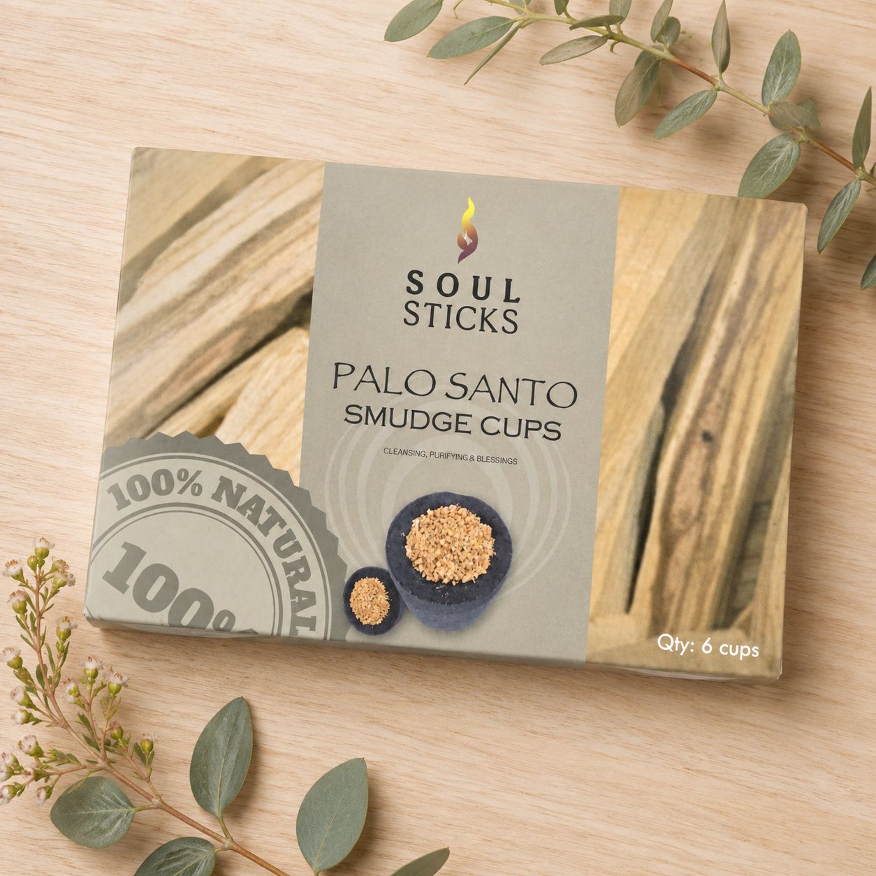 Soul Sticks Palo Santo Smudge Cups six-pack displayed on a light wooden table with greenery.