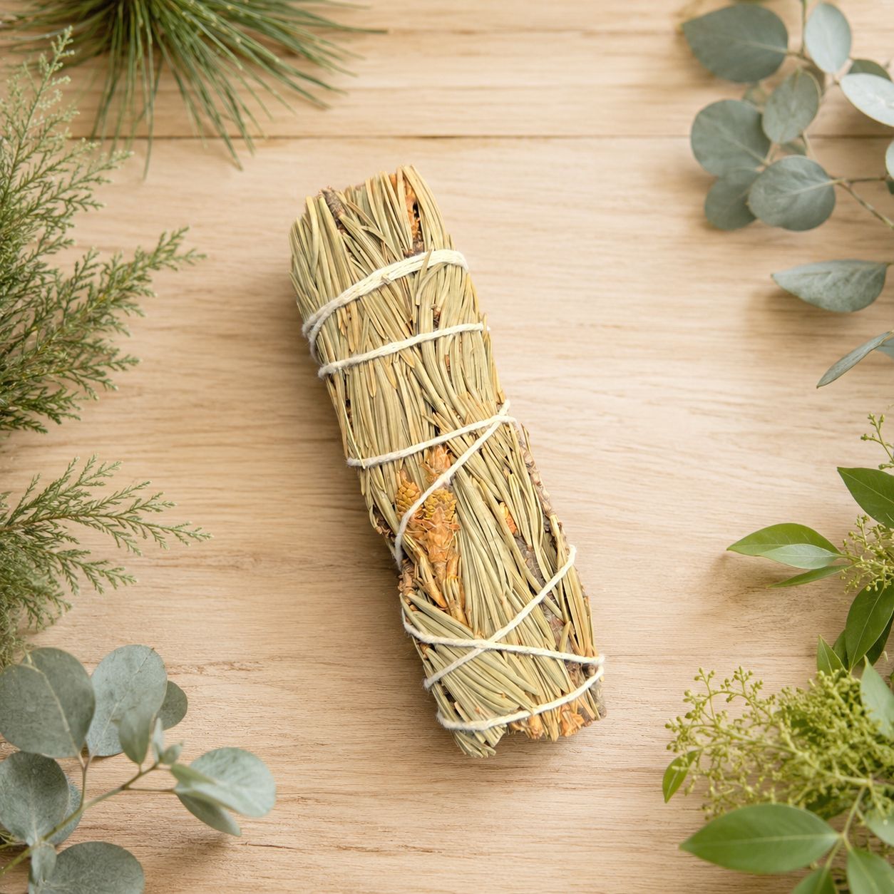 Pine smudge on a light wooden table with greenery