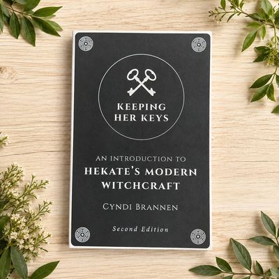 Keeping Her Keys by Cyndi Brannen displayed on a light wooden table with greenery.