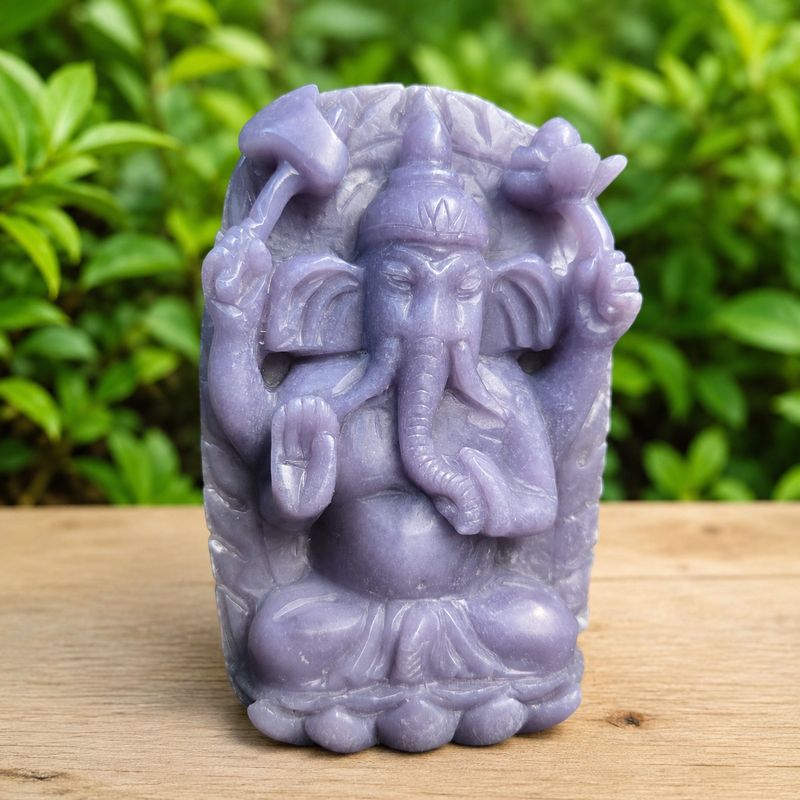 Unique purple jade Ganesha carving on wooden table with greenery background at Arkadys Metaphysical Gifts