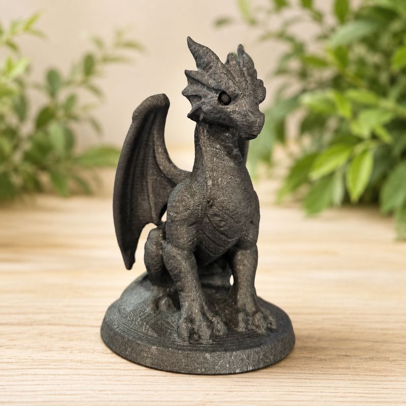 Shungite dragon carving on light wooden table with greenery background.