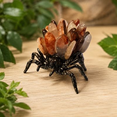 Fire quartz cluster spider on light wood table with greenery background
