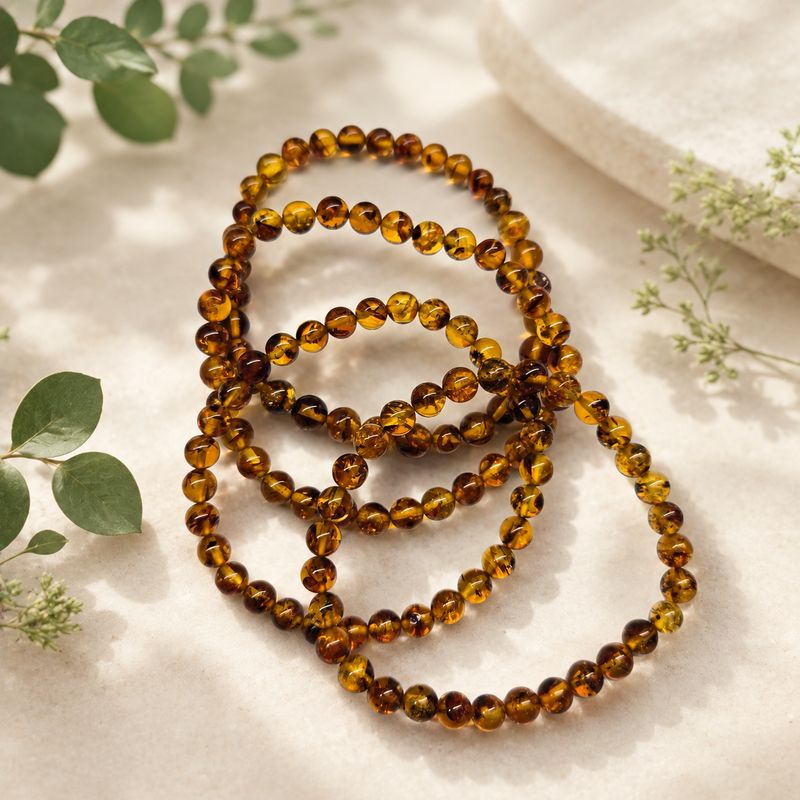 Natural Amber 6mm stretch bracelet with golden amber beads and greenery background.