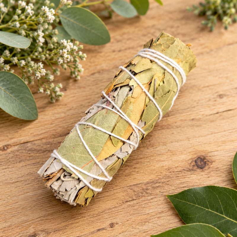 4-inch white sage and bay leaf smudge bundle tied with white string on a light wooden table with greenery