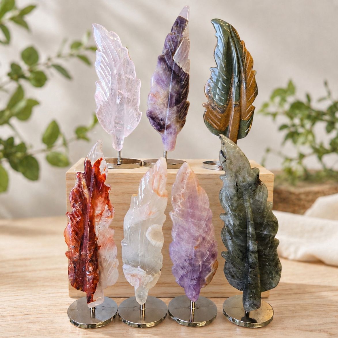 Mounted gemstone feather carvings in labradorite, rose quartz, amethyst, agate, fire quartz, and blue tiger eye on stands.