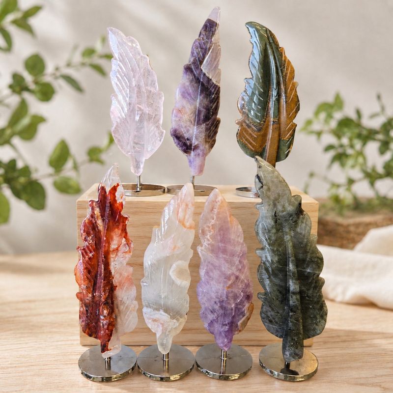 Mounted gemstone feather carvings in labradorite, rose quartz, amethyst, agate, fire quartz, and blue tiger eye on stands.