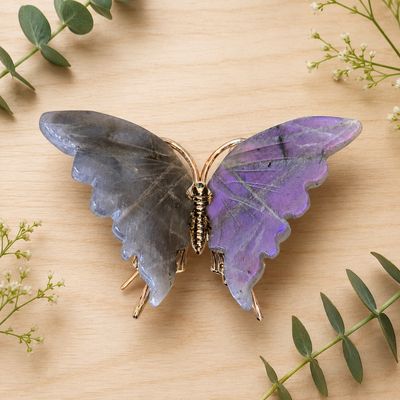 Labradorite butterfly carving on light wooden table with greenery