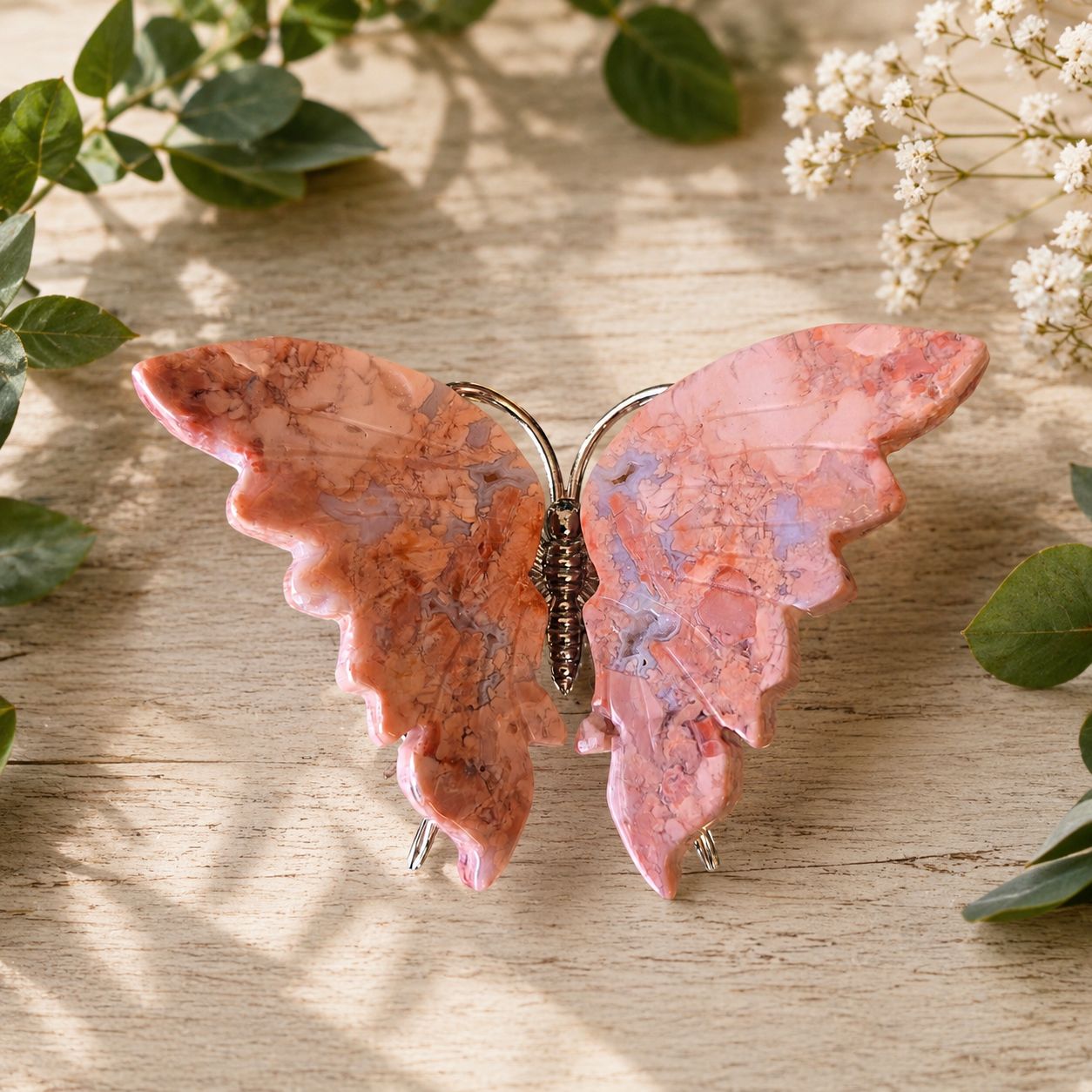 Cotton Candy Agate Butterfly at Arkady’s Metaphysical Gifts displayed on a wooden table with greenery.