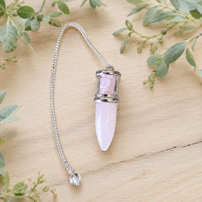 Rose Quartz Bullet Chips Pendulum with silver-toned chain and clear bead on a light wooden table