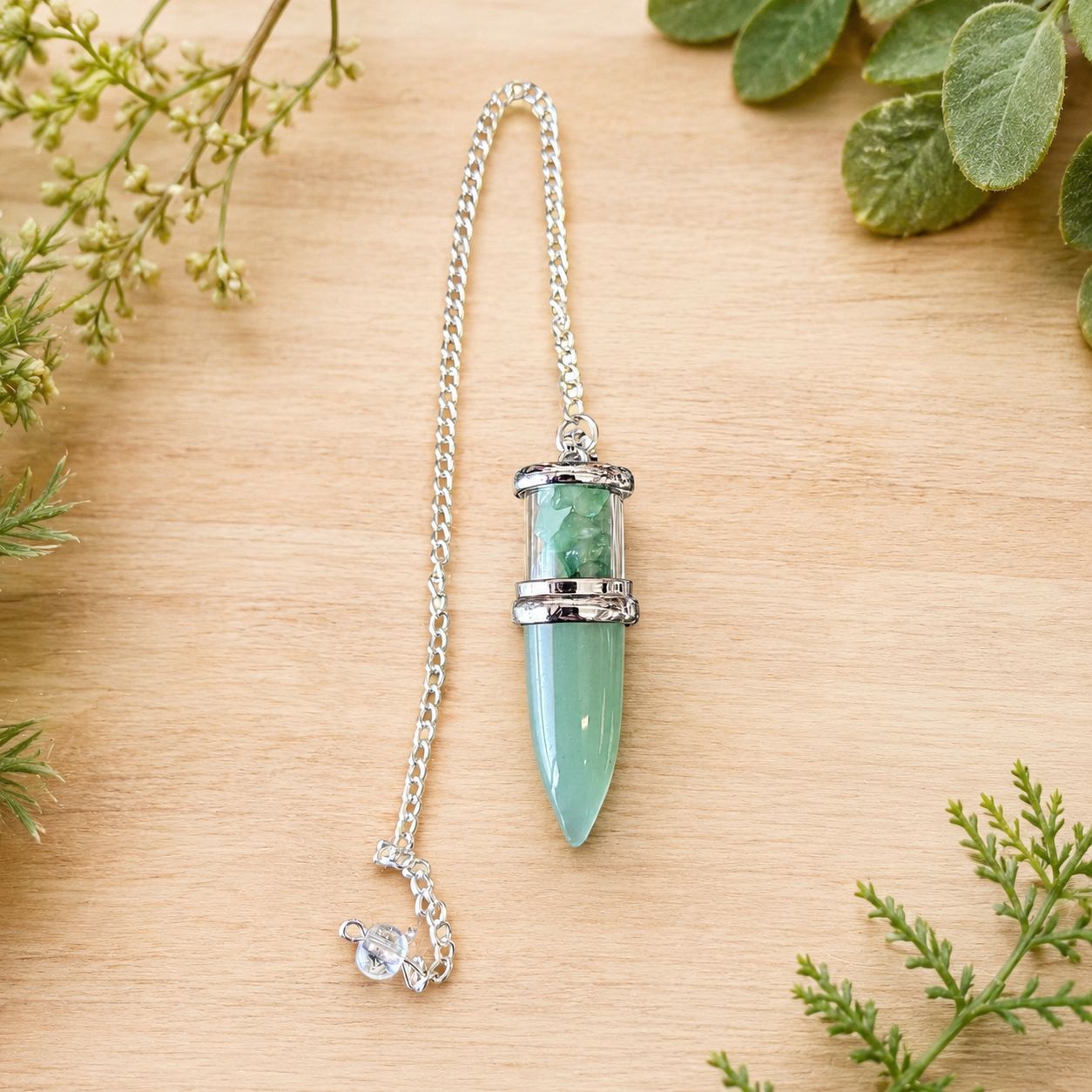 Green Aventurine Bullet Chips Pendulum with silver-toned chain displayed on a light wooden table